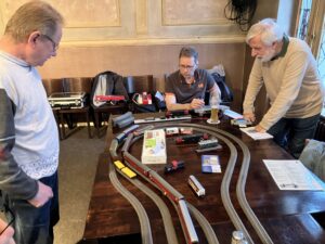 Modellbahnfans betrachten Tischbahnanlage.